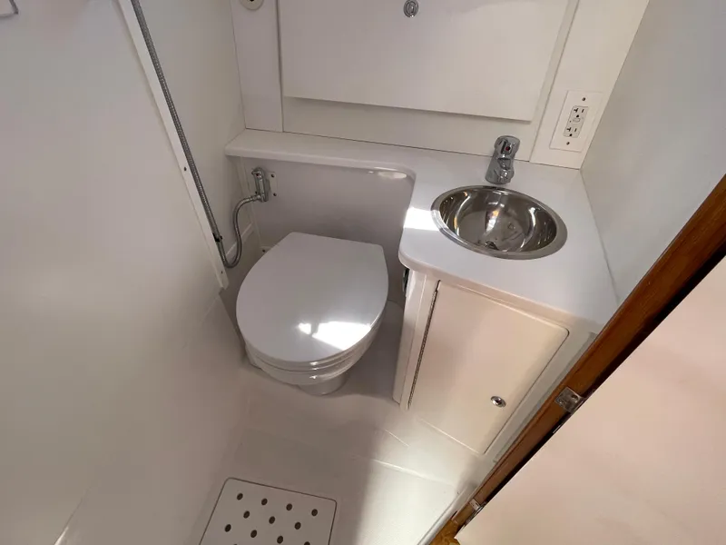 Slide: The Image of Compact bathroom in 2025 True North 34 Outboard Express boat, featuring toilet and sink. - 48