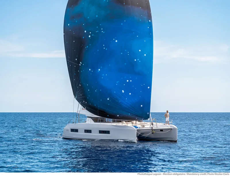 Slide: The Image of 2025 Lagoon 55 catamaran sailing with a starry blue sail on open sea. - 3