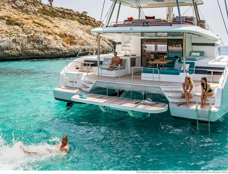 Slide: The Image of 2025 Lagoon 55 yacht in turquoise waters, people relaxing and swimming nearby. - 7