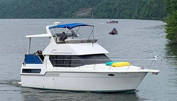 The Image of 1993 Carver 350 Aft Cabin yacht cruising on a serene lake with lush green surroundings. - 0