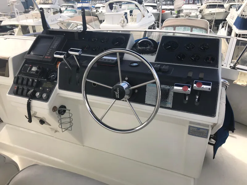 Slide: The Image of 1993 Carver 350 Aft Cabin helm with steering wheel and control panel at marina. - 10