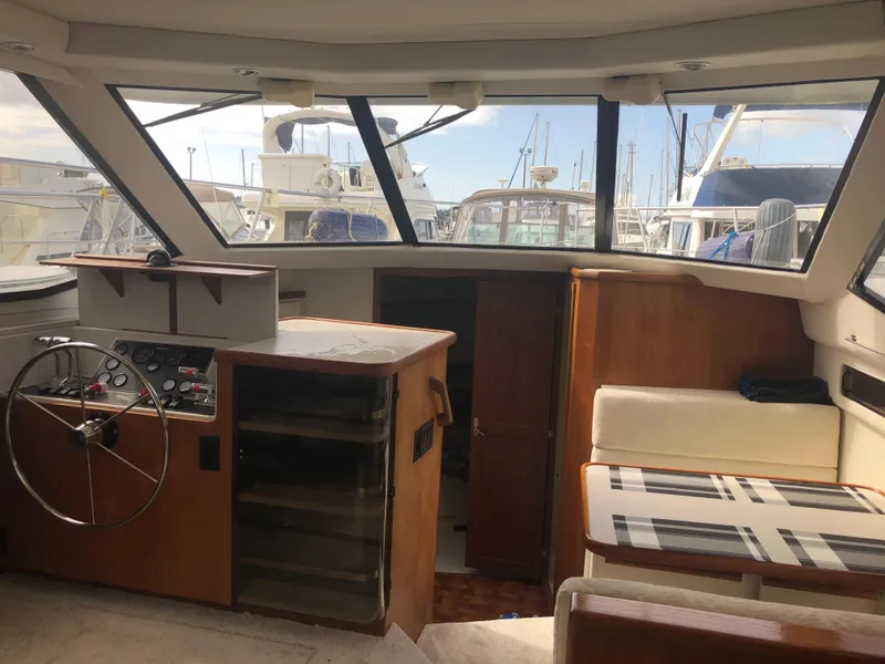 Slide: The Image of Interior of 1993 Carver 350 Aft Cabin yacht with helm, seating, and marina view. - 14