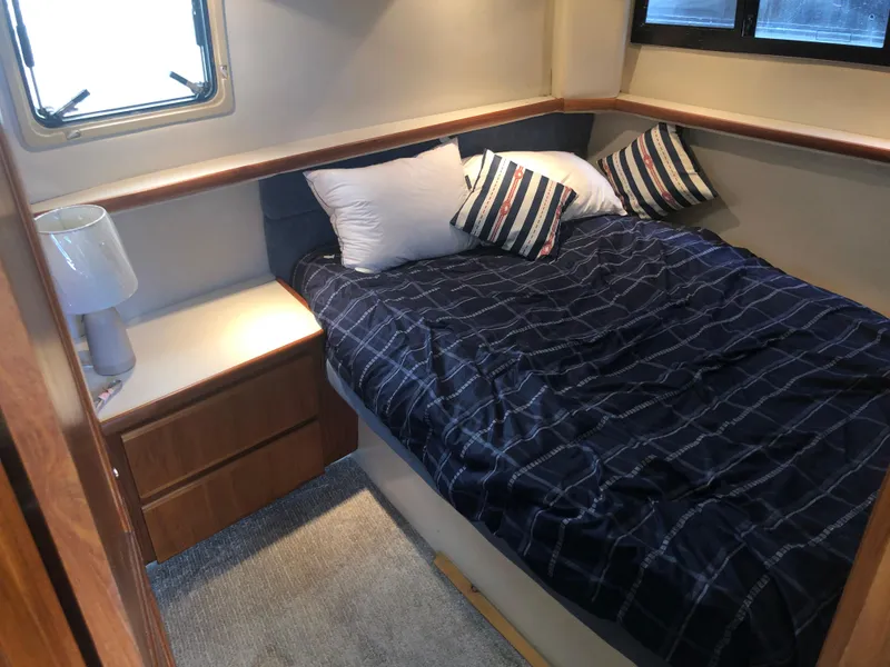 Slide: The Image of 1993 Carver 350 Aft Cabin bedroom with cozy bed, striped pillows, and bedside lamp. - 32