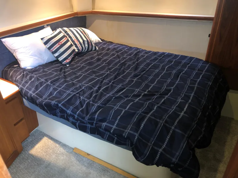 Slide: The Image of 1993 Carver 350 Aft Cabin bedroom with blue plaid bedding and striped pillows. - 33
