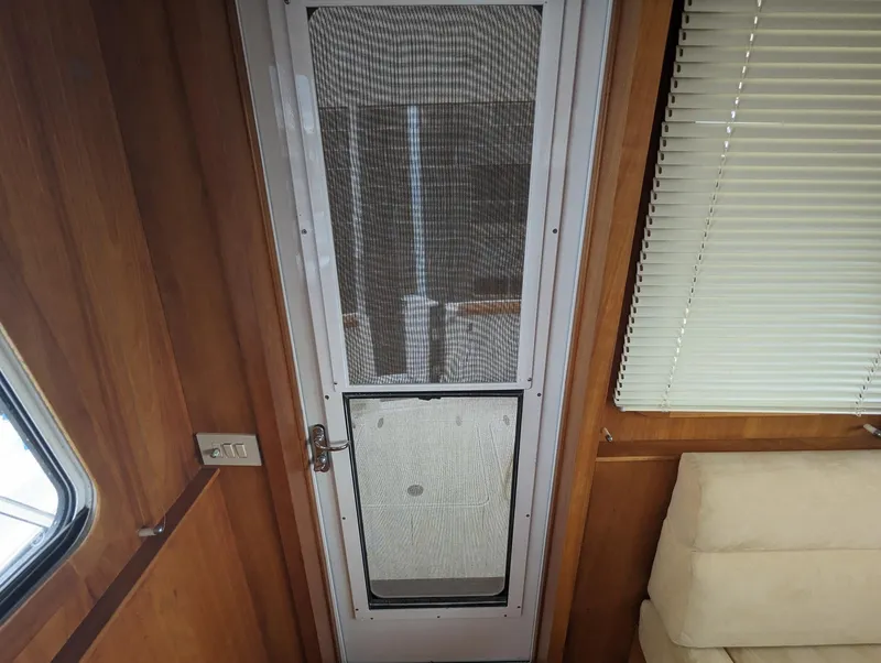 Slide: The Image of Interior of 2003 Sabre 36 Flybridge with screen door and wooden paneling. - 16