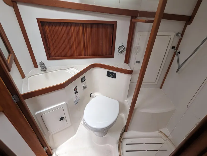 Slide: The Image of 2003 Sabre 36 Flybridge bathroom with toilet, sink, and wooden accents. - 17
