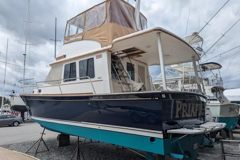 Slide: The Image of 2003 Sabre 36 Flybridge boat on stands, featuring a blue hull and tan flybridge cover. - 2
