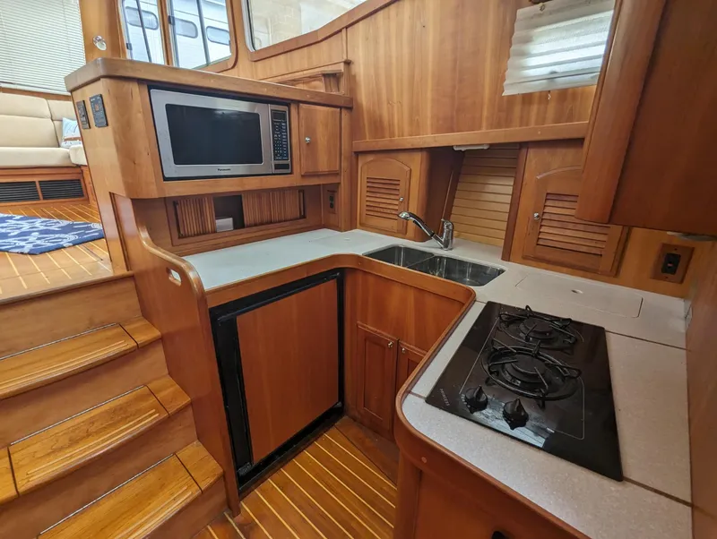Slide: The Image of 2003 Sabre 36 Flybridge yacht kitchen with wood cabinetry, microwave, sink, and stove. - 21