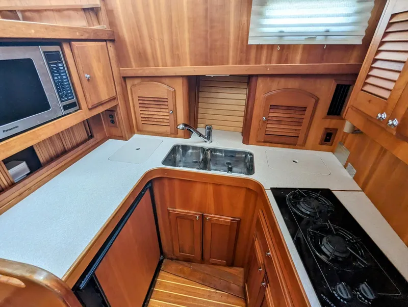 Slide: The Image of 2003 Sabre 36 Flybridge kitchen with wood cabinetry, sink, stove, and microwave. - 22