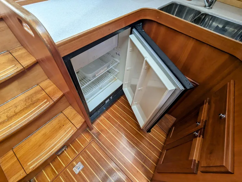 Slide: The Image of 2003 Sabre 36 Flybridge interior with open fridge, wooden flooring, and stairs. - 23