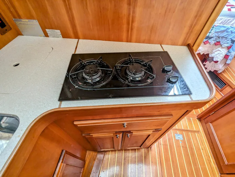 Slide: The Image of 2003 Sabre 36 Flybridge kitchen with two-burner stove and wooden cabinetry. - 24