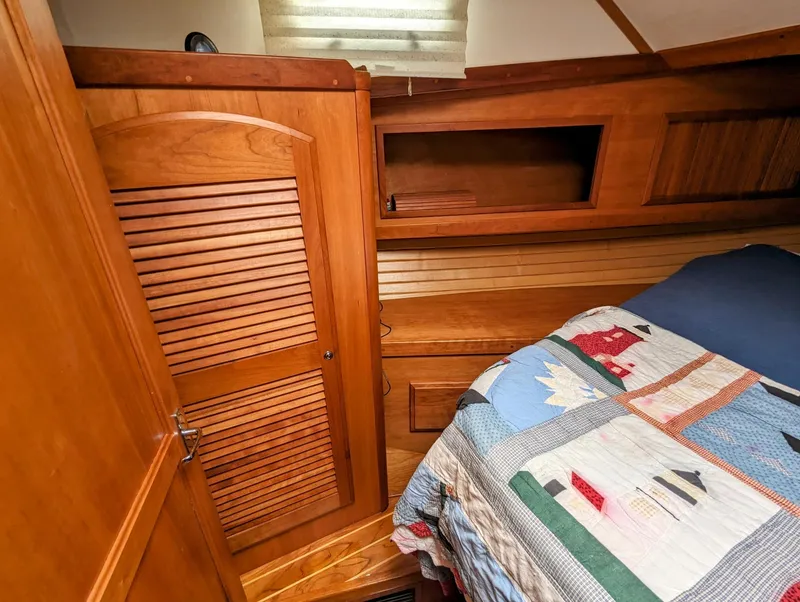 Slide: The Image of 2003 Sabre 36 Flybridge cabin interior with wooden cabinetry and colorful quilted bedspread. - 28