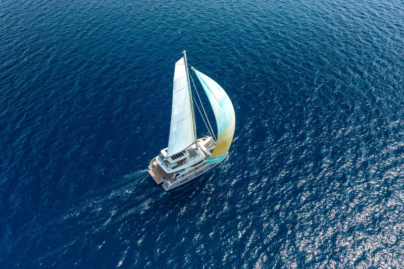 Slide: The Image of Aerial view of 2025 Lagoon 60 sailing on open blue sea. - 4