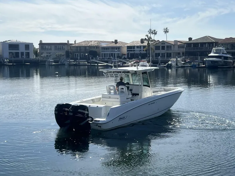 Slide: The Image of 2012 Boston Whaler 320 Outrage boat cruising in a calm marina with waterfront homes. - 12