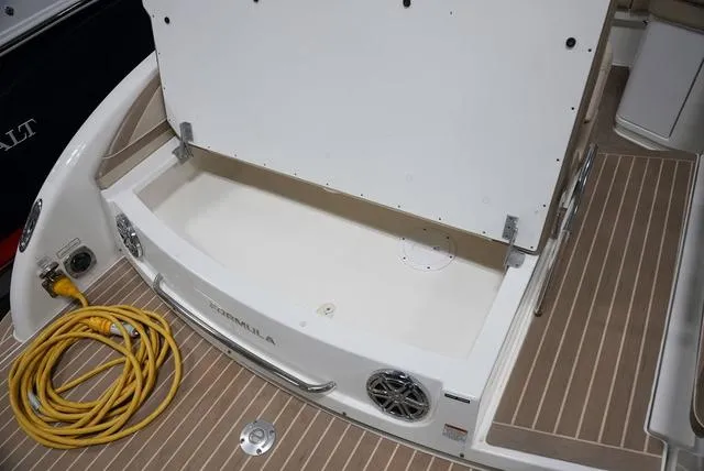 Slide: The Image of 2016 Formula Boats 290 Bowrider storage compartment with teak flooring and coiled yellow cable. - 7