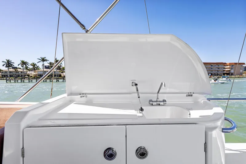 Slide: The Image of 2012 Beneteau Swift Trawler 44 outdoor sink with storage, docked by palm trees and buildings. - 15
