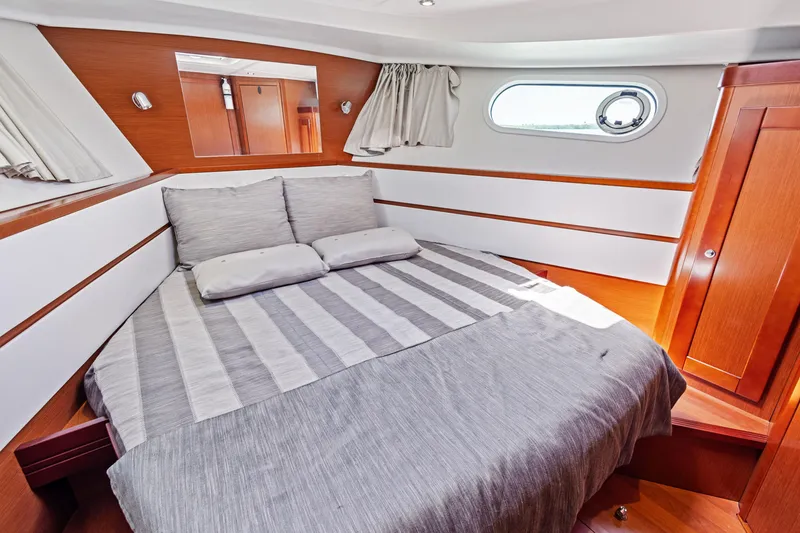 Slide: The Image of 2012 Beneteau Swift Trawler 44 cabin with cozy bed and wooden interior. - 24