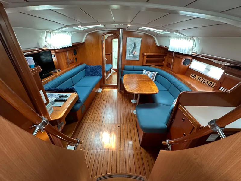 Slide: The Image of Spacious interior of 2002 Beneteau 411 sailboat with blue seating and wooden finishes. - 28