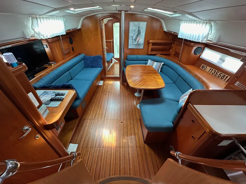Slide: The Image of Interior of 2002 Beneteau 411 yacht with blue seating and wooden finishes. - 29