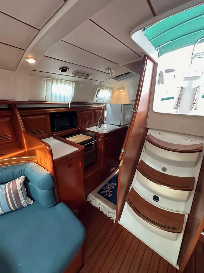 Slide: The Image of Interior of 2002 Beneteau 411 sailboat with cozy seating and compact kitchen area. - 31