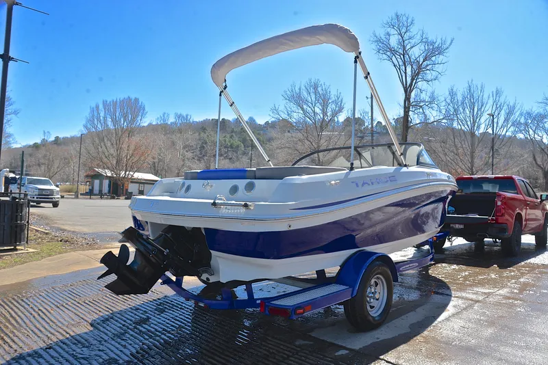Slide: The Image of 2015 Tahoe 500 TS boat on trailer, parked near a lake with trees in the background. - 12