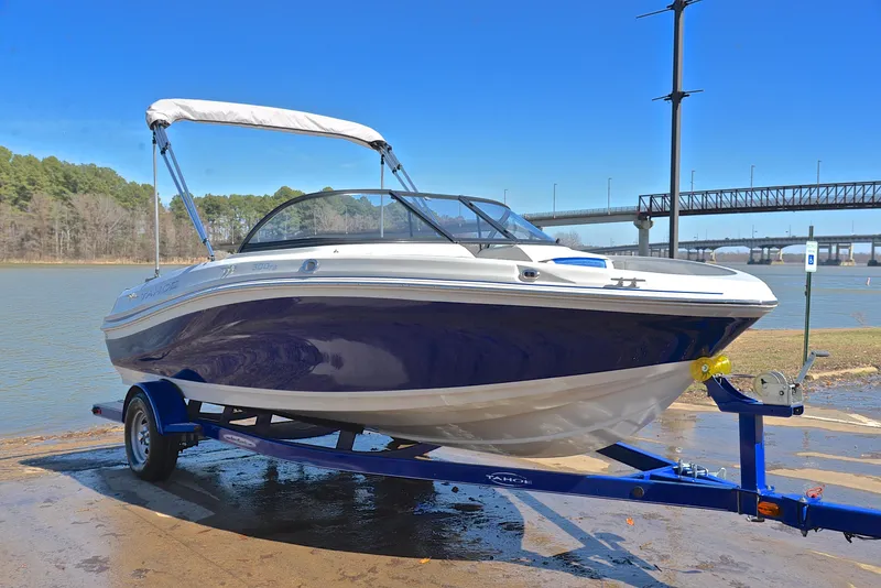 Slide: The Image of 2015 Tahoe 500 TS boat on trailer by a river, under clear blue sky. - 14