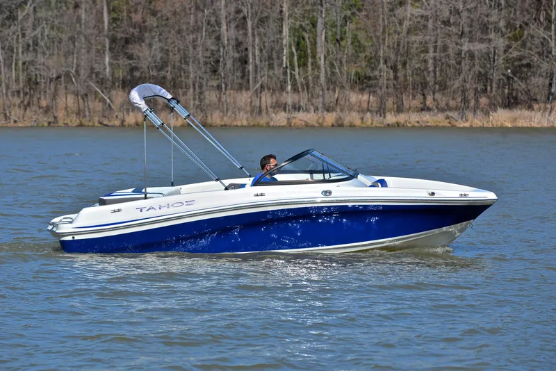 Slide: The Image of 2015 Tahoe 500 TS boat cruising on a lake with a forested shoreline. - 6