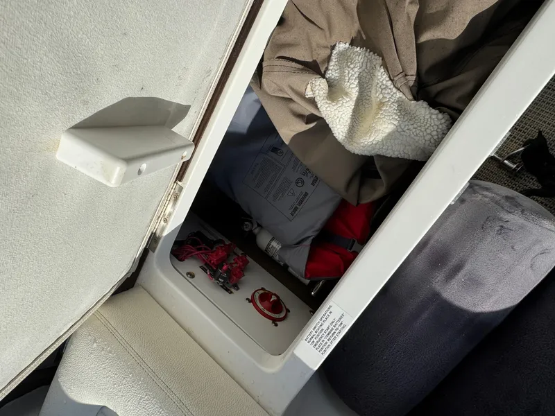 Slide: The Image of Storage compartment in a 2018 Cobalt R7 boat, containing various items and a control panel. - 26