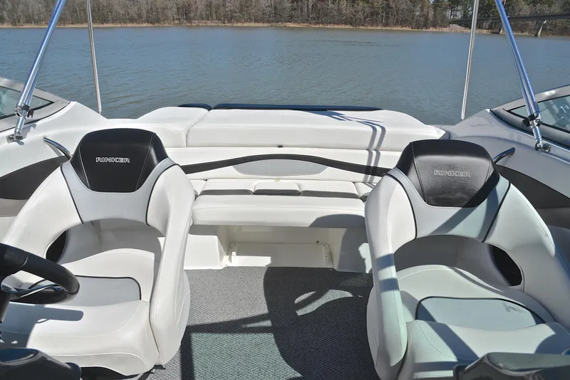 Slide: The Image of 2014 Rinker 196 Captiva boat interior with two seats, on a calm lake. - 22