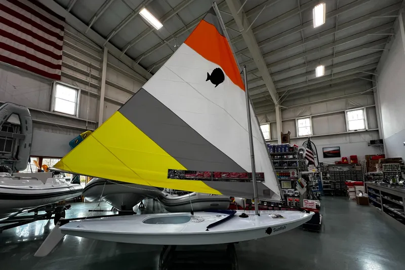 The Image of 2024 Sunfish Laser sailboat with colorful sail displayed indoors. - 0