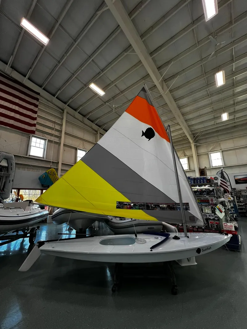 Slide: The Image of 2024 Sunfish Laser sailboat with colorful sail displayed indoors. - 2