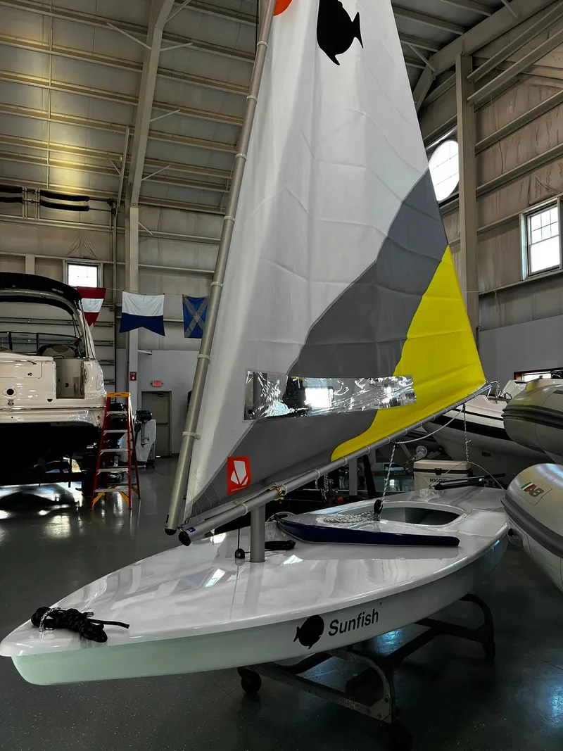 Slide: The Image of 2024 Sunfish Laser sailboat with colorful sail in indoor showroom. - 3