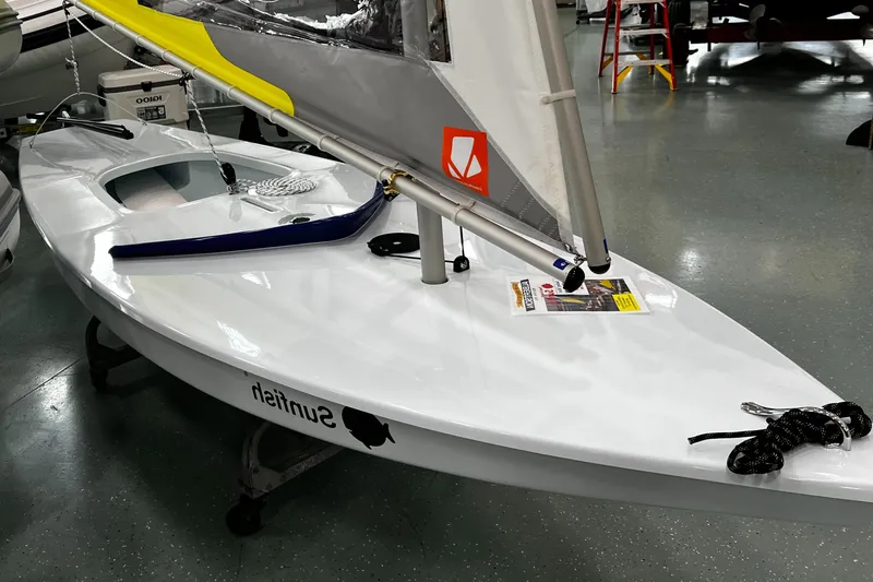 Slide: The Image of 2024 Sunfish Laser sailboat in showroom, featuring sleek white design and vibrant sail. - 5