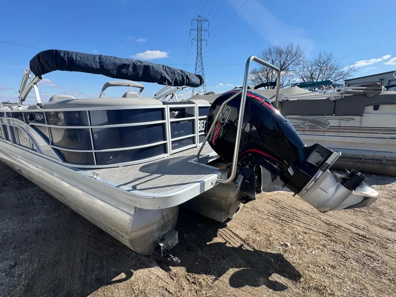 Slide: The Image of 2022 Bennington 23 SXSR pontoon boat with outboard motor, parked on sandy ground. - 15