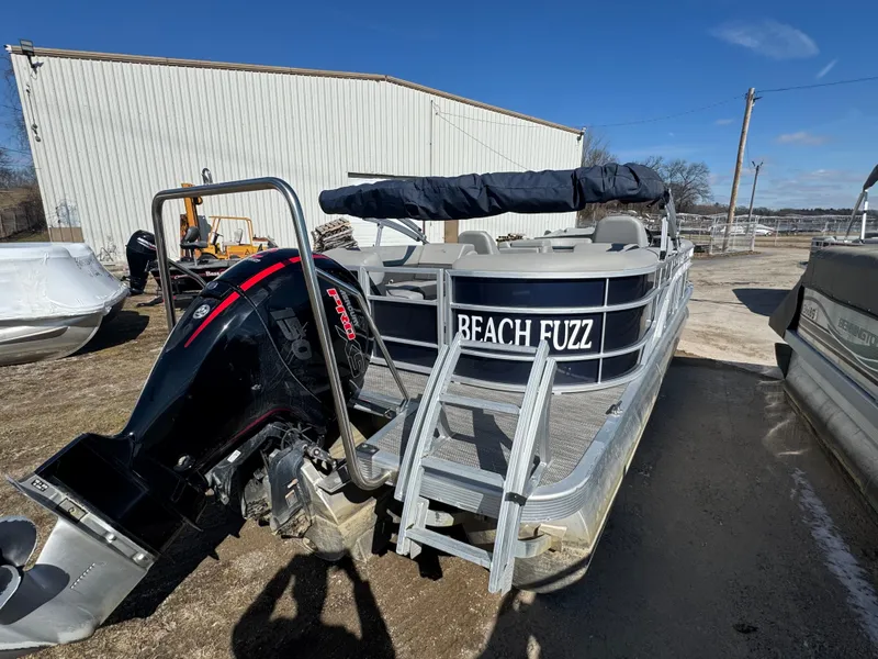 Slide: The Image of 2022 Bennington 23 SXSR pontoon boat with "Beach Fuzz" name, parked outdoors. - 16