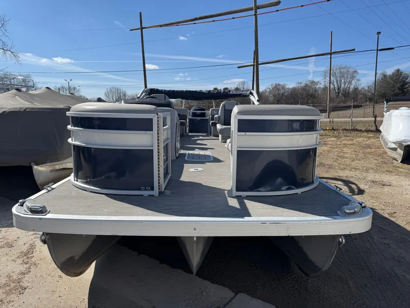 Slide: The Image of 2022 Bennington 23 SXSR pontoon boat on land, showcasing spacious deck and seating. - 2