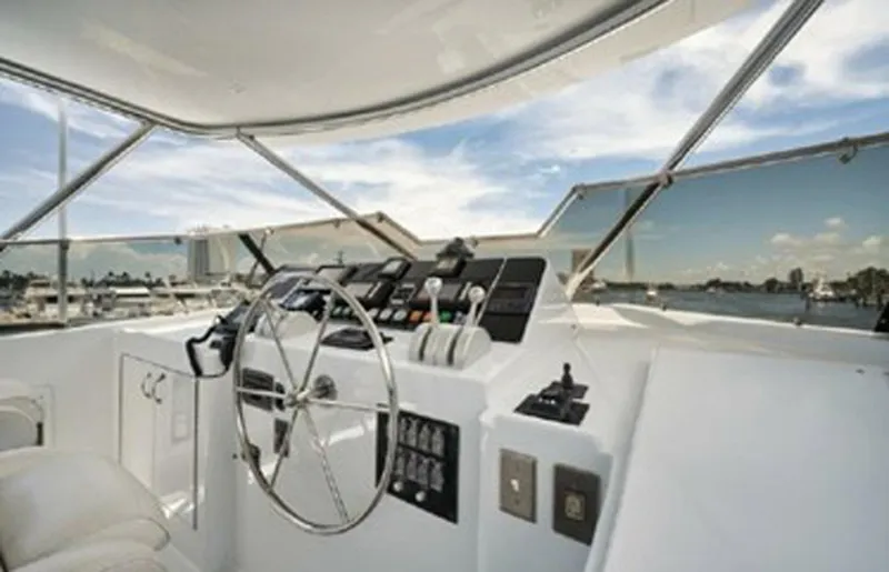 Slide: The Image of 1998 Hatteras 74 Cockpit Motor Yacht helm with steering wheel and controls, overlooking marina. - 45
