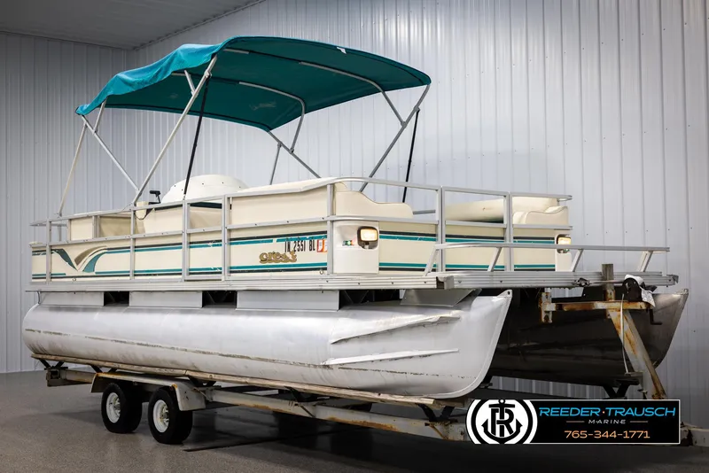 Slide: The Image of 1998 Crest 22 DLX pontoon boat with teal canopy on trailer in indoor storage. - 3