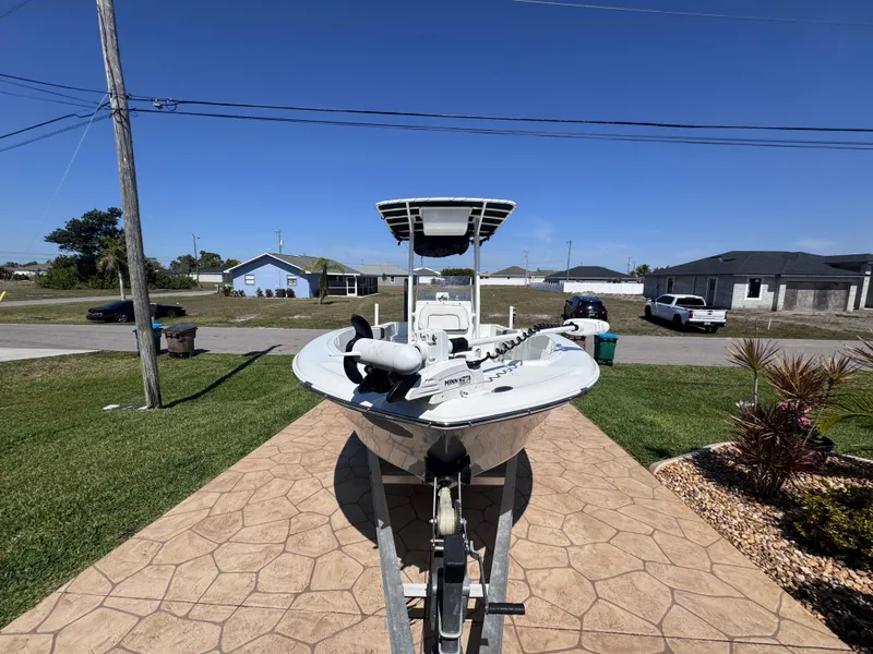 The Image of 2021 Clearwater 2000 C/C boat on trailer at dealership under cloudy sky. - 0