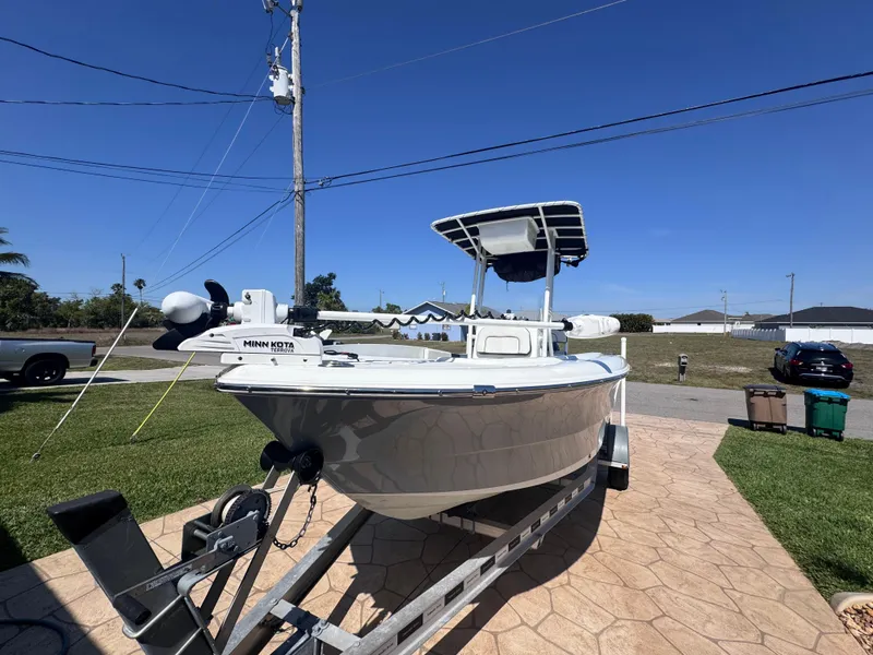 Slide: The Image of 2021 Clearwater 2000 C/C boat on trailer, featuring Suzuki outboard motor, under cloudy sky. - 2