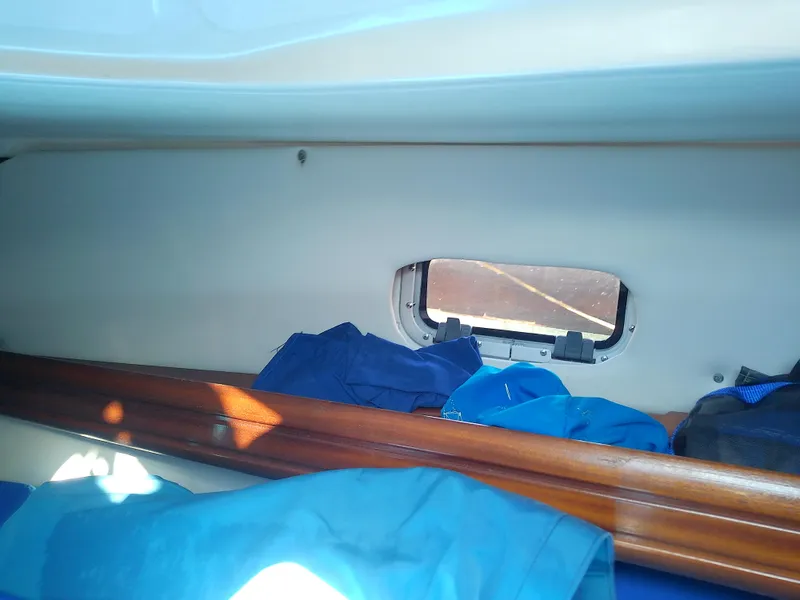 Slide: The Image of Interior cabin view of a 2001 Bavaria 37 Cruiser sailboat with clothes and a small window. - 45