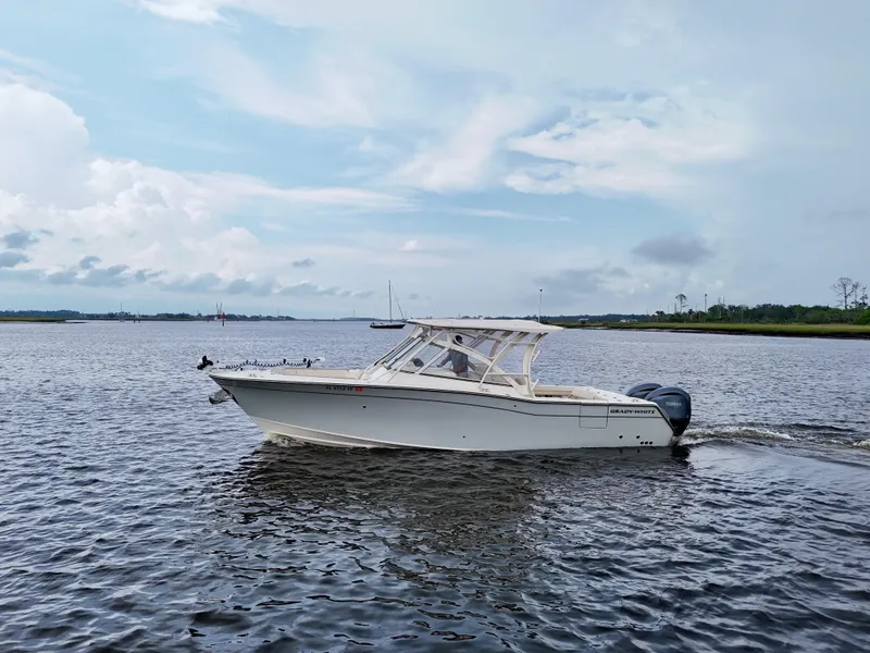 Slide: The Image of 2022 Grady-White Freedom 307 boat cruising on a calm river under a cloudy sky. - 10