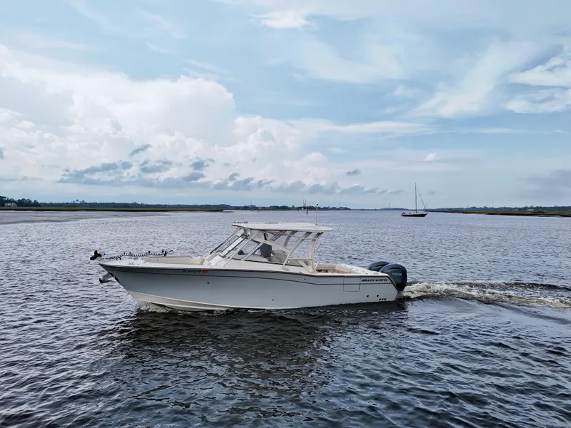 Slide: The Image of 2022 Grady-White Freedom 307 boat cruising on a calm river under a cloudy sky. - 11