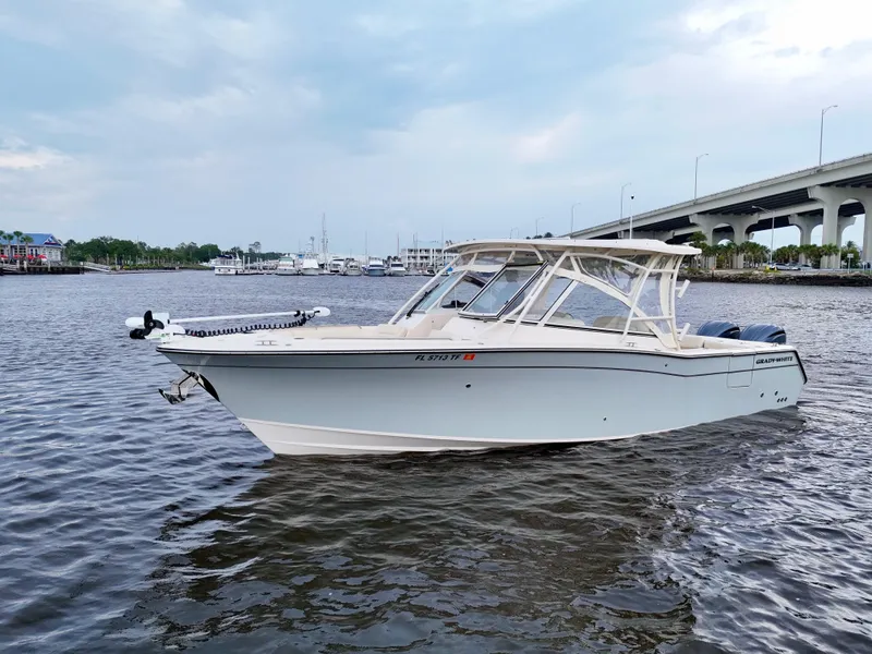 Slide: The Image of 2022 Grady-White Freedom 307 boat on water near a bridge and marina. - 14