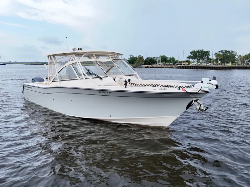 Slide: The Image of 2022 Grady-White Freedom 307 boat cruising on a calm river under a cloudy sky. - 16