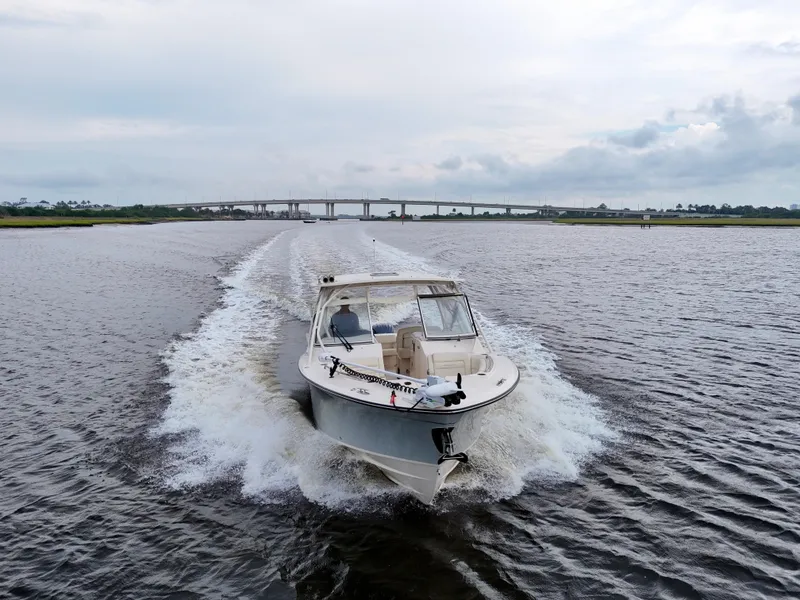 Slide: The Image of 2022 Grady-White Freedom 307 boat cruising on a river with a bridge in the background. - 3