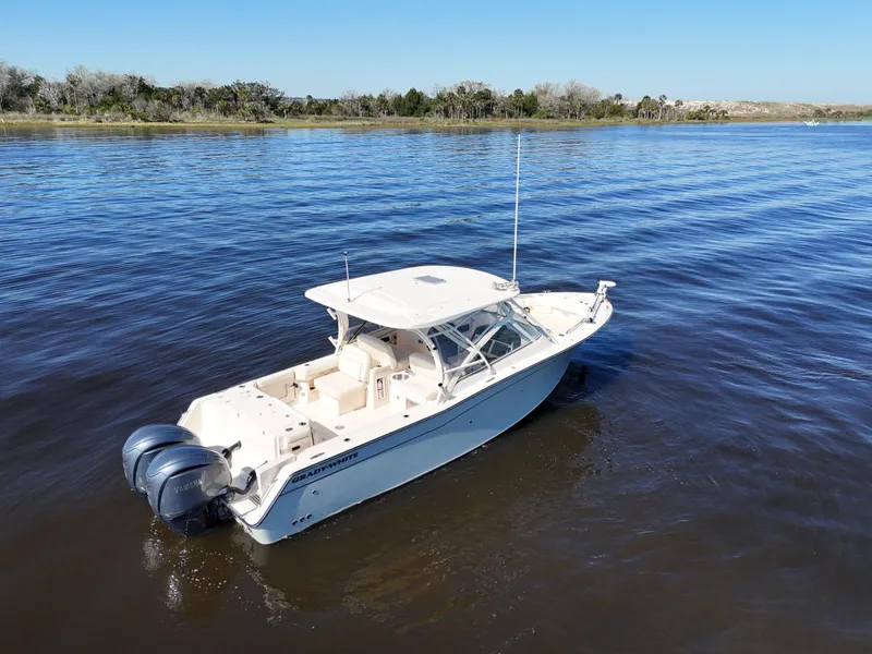 Slide: The Image of 2022 Grady-White Freedom 307 boat on calm water, featuring dual outboard engines. - 32