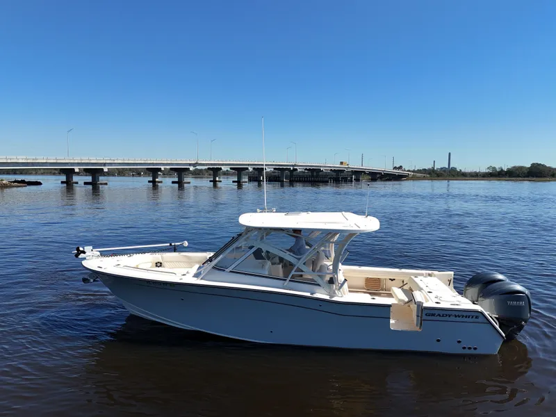 Slide: The Image of 2022 Grady-White Freedom 307 boat on calm water near a bridge under clear blue sky. - 34