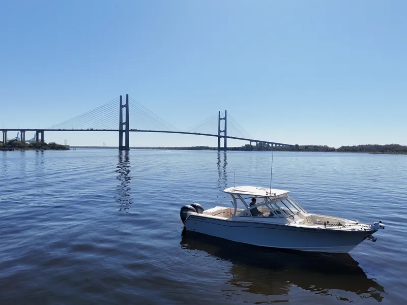 Slide: The Image of 2022 Grady-White Freedom 307 boat on calm water near a large suspension bridge. - 36