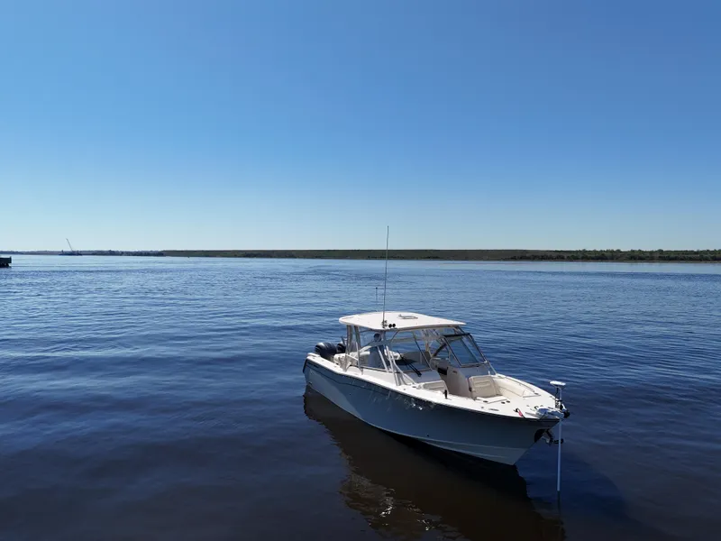Slide: The Image of 2022 Grady-White Freedom 307 boat on calm water under clear blue sky. - 38